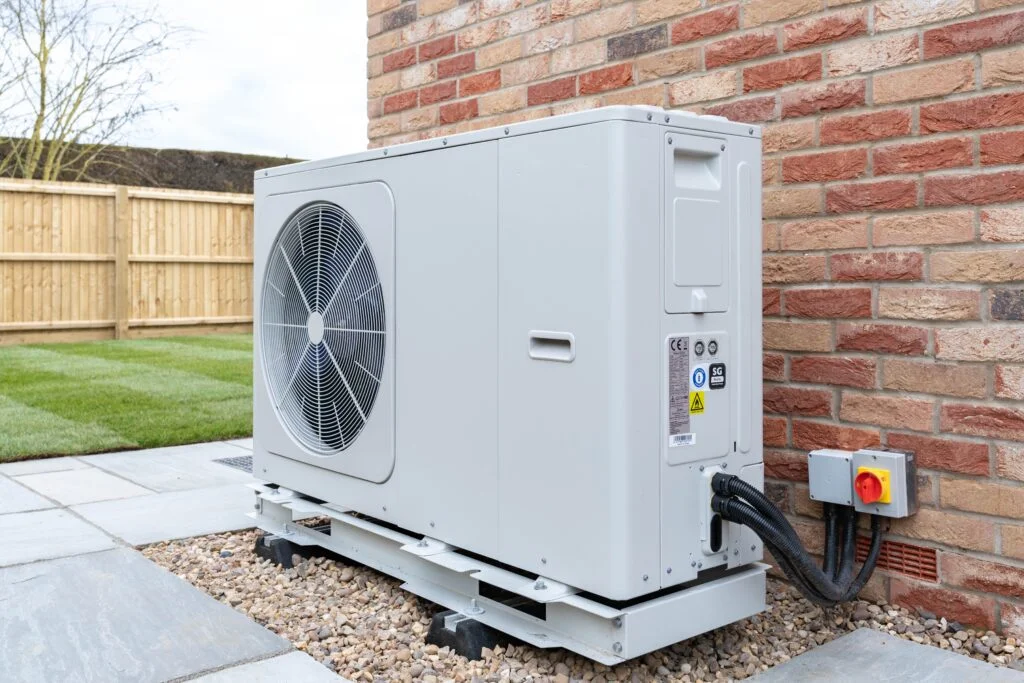 Air source heat pump in front of brick wall
